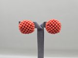 a close up of a pair of orange beaded earrings