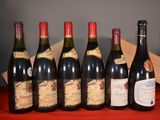 six bottles of wine are lined up on a red table