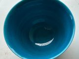 a blue bowl sitting on a table with a white background