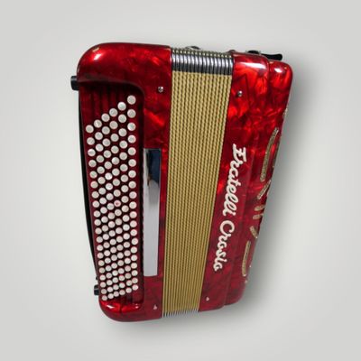 an old red accordion hanging on a white wall