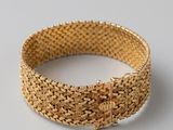 gros plan d'un bracelet en or sur une surface blanche