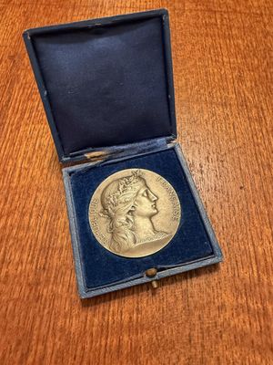 a gold medal in a blue case on a wooden table