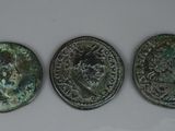 trois pièces de monnaie romaines anciennes, dont l'une présente un revers et l'autre un avers
