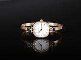 a gold bracelet with a watch on it on a black surface