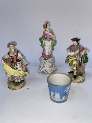 trois figurines représentant des personnes sont assises à côté d'une tasse posée sur une table