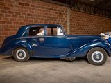 a blue car parked in a garage next to a brick wall