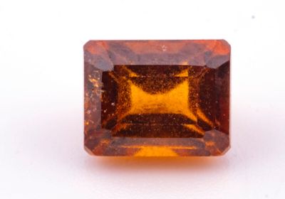 un gros plan d'un saphir orange taillé en carré posé sur une surface blanche