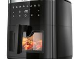 une friteuse à air chaud noire contenant des aliments, posée sur une surface blanche