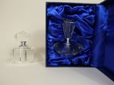 a small glass bottle in a blue box next to a small glass bottle
