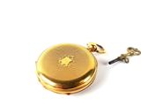 a gold pocket watch with a key attached to it