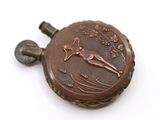 a small bronze pocket watch with a bird on it