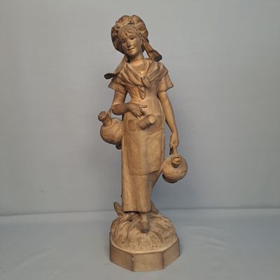 statue d'une femme tenant un oiseau et un pot, posée sur un socle