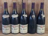 six bottles of wine are lined up on a wooden shelf