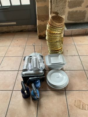 une pile d'assiettes et de casseroles posée par terre, à côté d'une pile d'assiettes