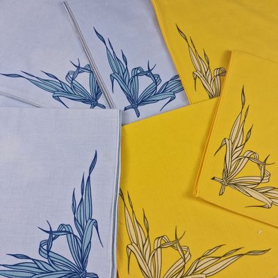 des serviettes jaunes et blanches ornées de fleurs bleues, posées sur une table