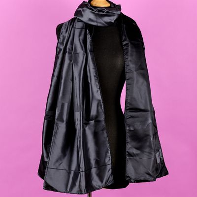 une femme portant une cape noire, un haut noir et un pantalon noir