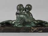 bronze sculpture of two women sitting on a marble base