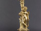 a gold plated candelab with a statue of a man holding a candelab