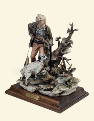 figurine représentant un homme armé d'un pistolet, accompagné d'un chien, assis sur un rocher
