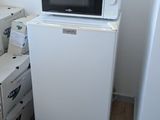 un petit réfrigérateur blanc et un micro-ondes dans une petite pièce