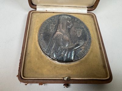une petite médaille en argent dans un écrin posé sur une table
