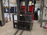 a forklift in a warehouse with a red container in the background