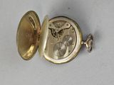 a gold pocket watch with a gold case on a white surface