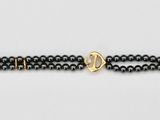 a close up of a black beaded bracelet on a white surface