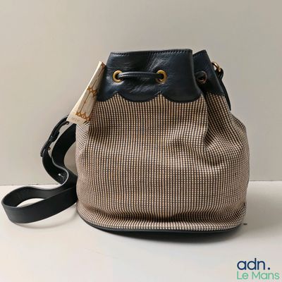 beige and black houndsered bucket bag with black leather handles