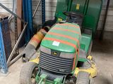 une tondeuse à gazon verte garée dans un garage à côté d'un tracteur vert