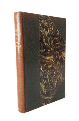 un vieux livre à la couverture dorée et noire posé sur une surface blanche