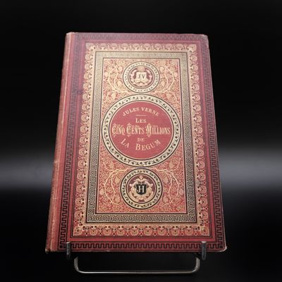 un vieux livre posé sur un support métallique, sur une surface noire