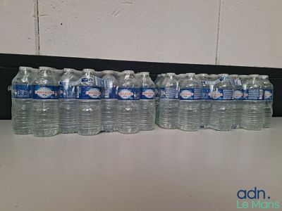 Plusieurs bouteilles d'eau sont alignées sur une table