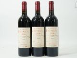 trois bouteilles de vin rouge sont alignées sur une surface blanche