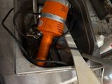 an orange electric driller in a sink with a spatula in it