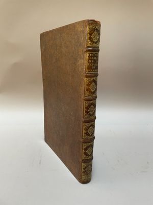 un livre brun avec des bordures dorées posé sur une surface blanche