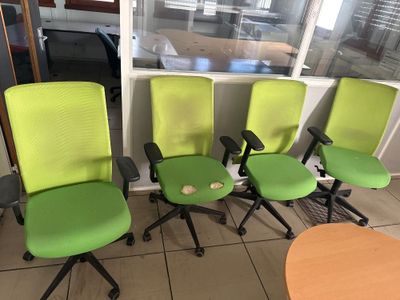 trois chaises de bureau vertes placées devant une fenêtre dans un bureau