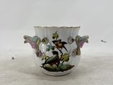 a small white vase with a bird and flowers on it