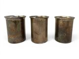 three metal vases sitting next to each other on a white surface