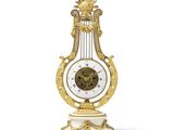 une horloge dorée et blanche posée sur un socle, sur une surface blanche
