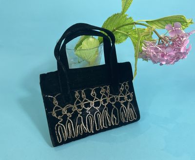 black velvet handbag with gold threadwork and flowers on a blue background