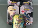 several tins of pokemon cards are sitting on a table