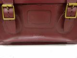 leather satchel bag with brass buckles on a white surface