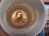 a person holding a cup with a picture of jesus in it