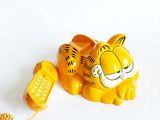 a yellow phone with a tiger on it and a cat on top of it