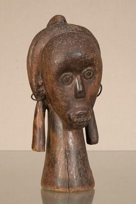 une vieille sculpture en bois représentant la tête d'une femme portant des boucles d'oreilles