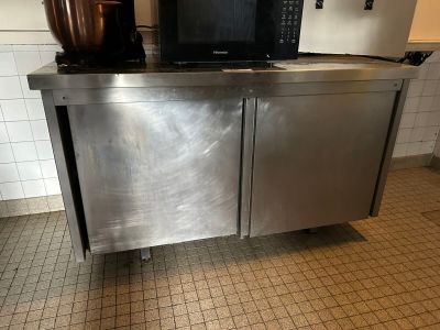 a stainless steel cabinet with a microwave on top of it