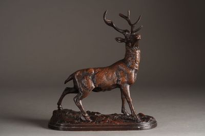bronze sculpture of a stag standing on a rock on a gray background