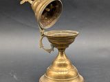 brass plated cup with a bell on a stand on a gray background