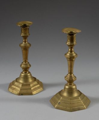 pair of antique brass candlesticks on a grey background